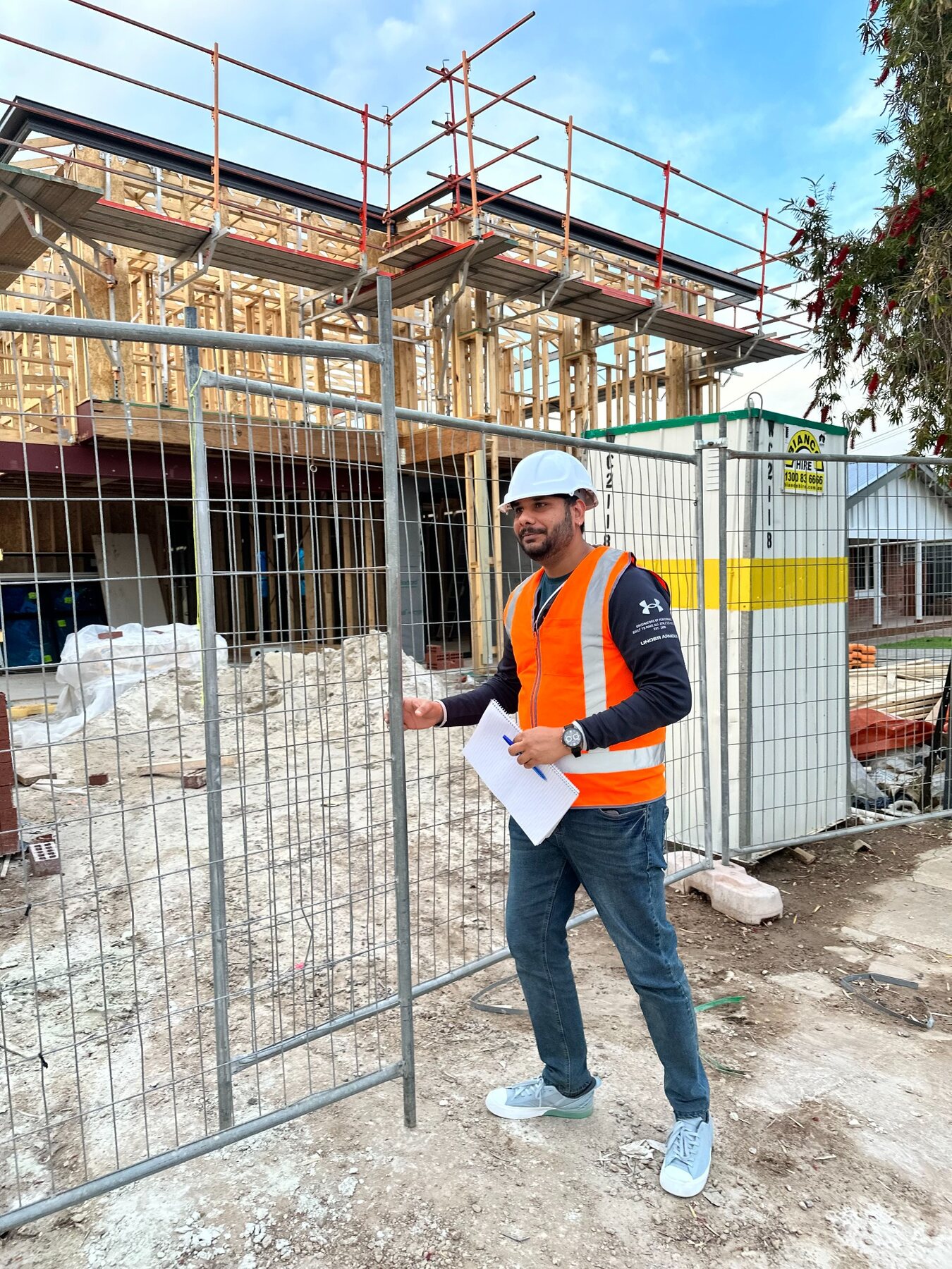 Imon Hussain standing at an active residential construction site with plans in hand